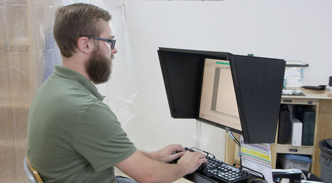 Man at a computer that has an indoor-outdoor monitor hood installed on it