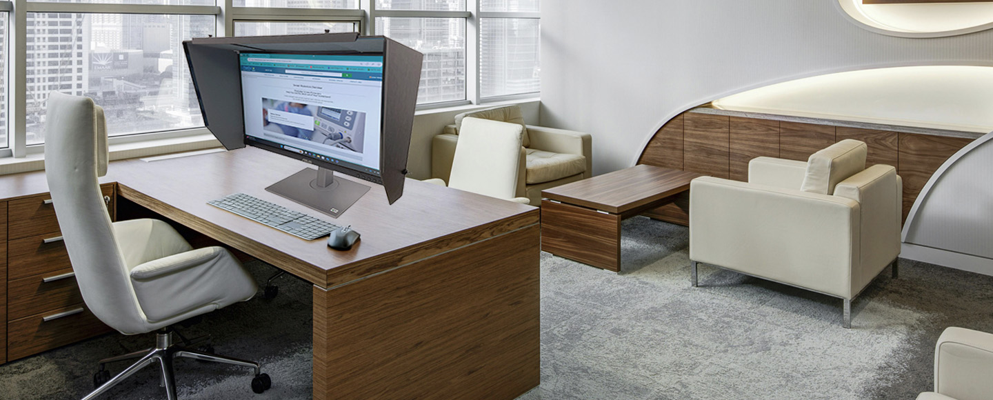 Computer on a desk with a monitor hood
